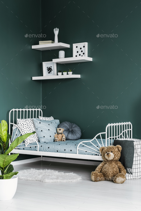 Teddy bear toy by a white twin bed in a dark green bedroom inter Stock Photo by bialasiewicz