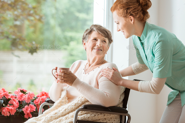 A professional caretaker in uniform helping a geriatric female p - Stock Photo - Images