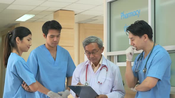 Team of asian doctor nurse consult together on patients file at hospital. alt