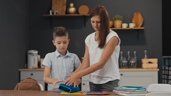 Mom Helps Her Son Prepare a Backpack for School