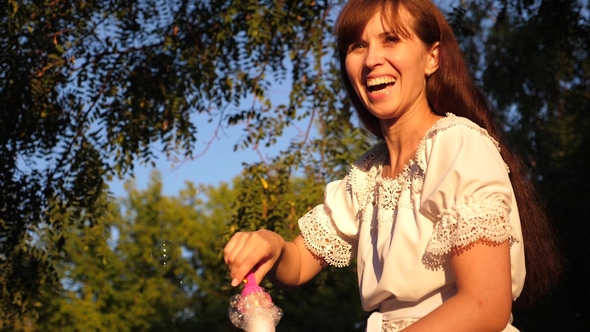 Merry Girl Laughs and Launches Big Soap Bubbles in the City Park and Smiles