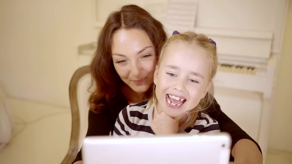 Mother and Daughter Playing on the Computer Together in a Bright Living Room. Mom and Girl Gently To alt