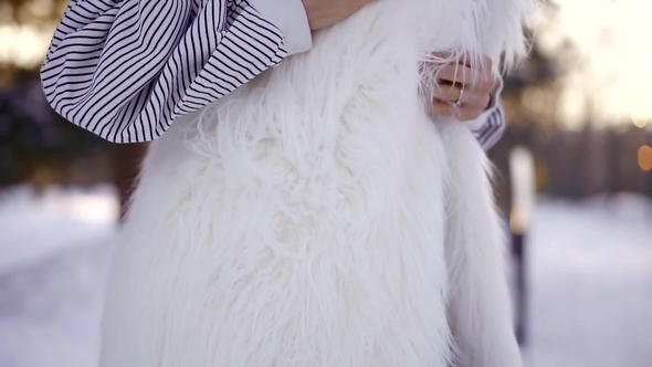 Young Beautiful Girl Spends Her Hand with Red Nails on a White Fur Vest alt