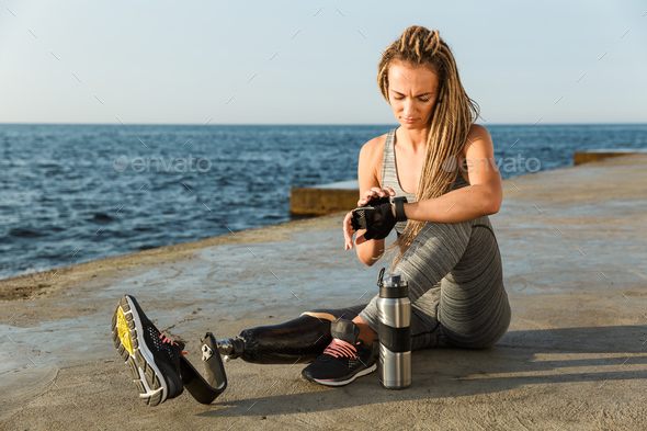 Smiling disabled athlete woman with prosthetic leg Stock Photo by vadymvdrobot