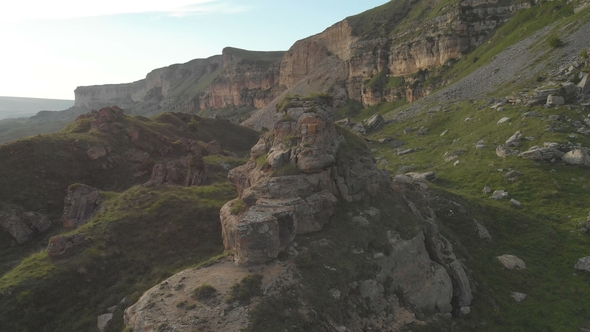 Flying Around a Large Rock Formation Standing at the Foot of the Epic Edge of a Rocky Plateau