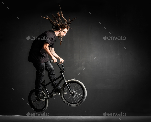 Young sportsman doing stunts on his professional bicycle. Stock Photo by photocreo