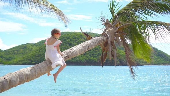 Adorable Little Girl at Tropical Beach Sitting on Palm Tree During Summer Vacation alt