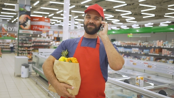 Handsome Grocery Delivery Man Talking To Mobile and Holding Grocery Paper Bag