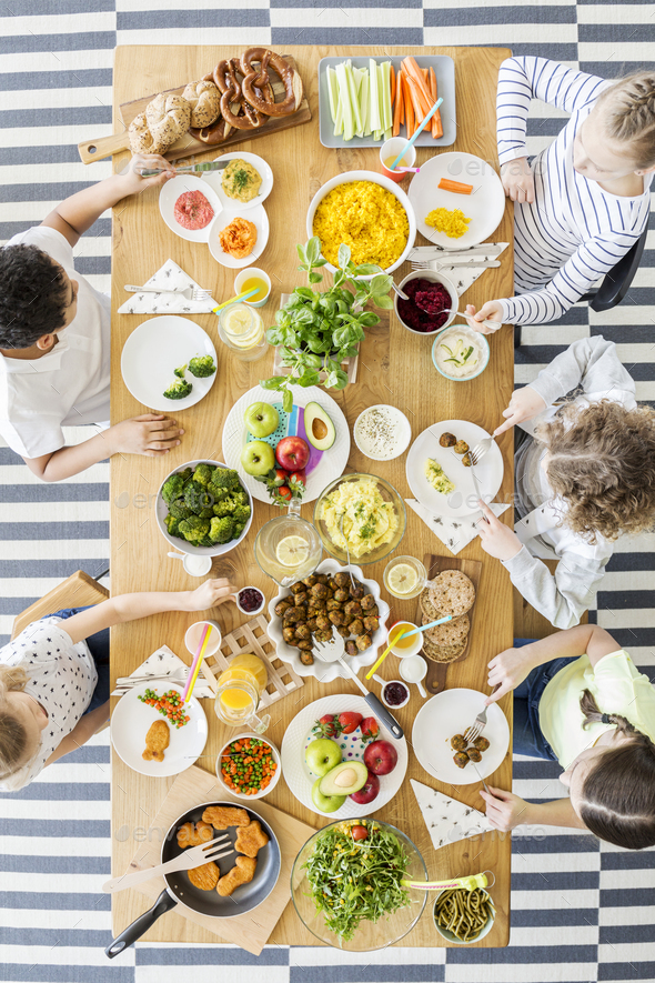 Top view of children eating healthy homemade meal. Wooden table Stock Photo by bialasiewicz