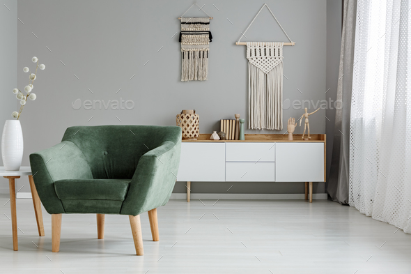 Real photo of a green armchair standing in a bright living room - Stock Photo - Images