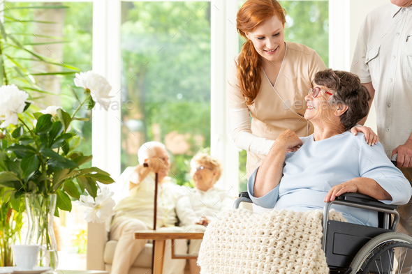 Tender caregiver saying goodbye to an elderly pensioner in a whe - Stock Photo - Images
