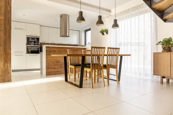 Spacious, open kitchen and dining room with wooden table and cha - Stock Photo - Images
