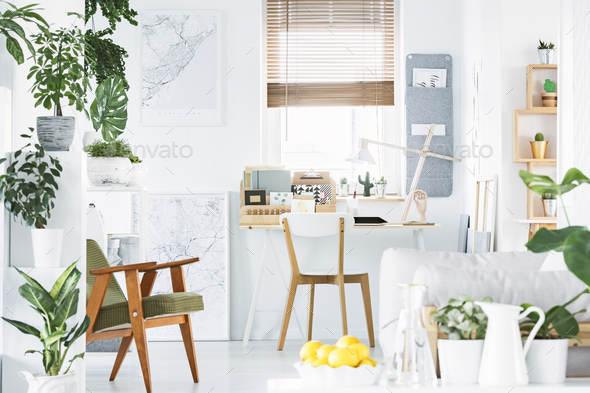 Creative home office interior with a retro armchair, desk, windo Stock Photo by bialasiewicz