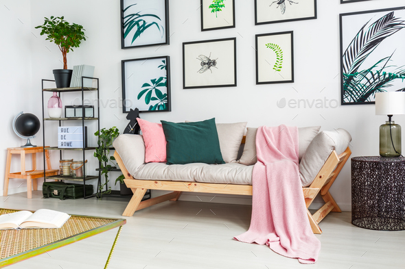 Real photo of a sofa standing next to a wall with paintings and - Stock Photo - Images