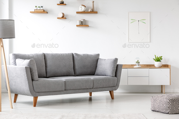 Simple, gray sofa standing next to a white cupboard in living ro Stock Photo by bialasiewicz