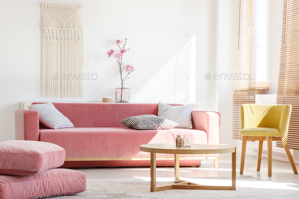 Real photo of a pink couch with pillows standing next to big pil Stock Photo by bialasiewicz