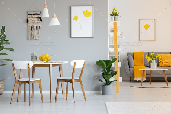 Two white lamps above a round dining table in open space apartme Stock Photo by bialasiewicz