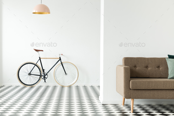 Bike against an empty wall, cropped sofa and checkered floor in Stock Photo by bialasiewicz