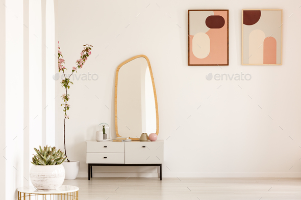 Plant on table and mirror on white cabinet in simple living room Stock Photo by bialasiewicz