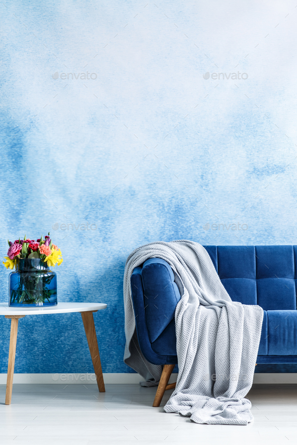 Comfortable dark blue settee with gray blanket and small side ta Stock Photo by bialasiewicz