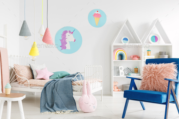 Furry pink pillow on a vibrant blue armchair in a sweet kid bedr - Stock Photo - Images