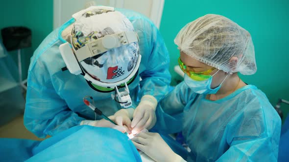 Patient receiving plastic operation. Surgeon and his assistant performing cosmetic surgery alt