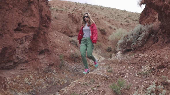Girl Tourist in Sunglasses Goes on an Unusual Terrain Red Mountains and Red Earth As on Mars