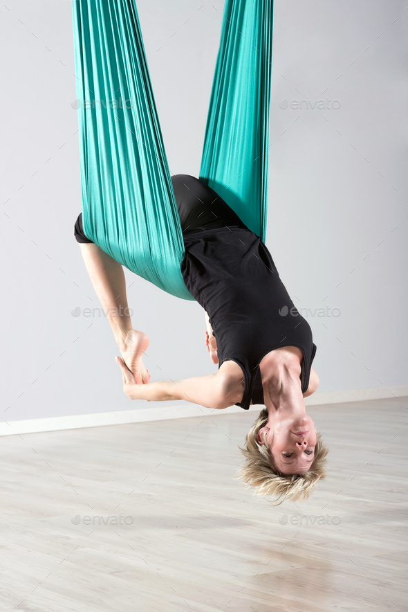 Upside down woman doing aerial yoga back bends Stock Photo by Photology75