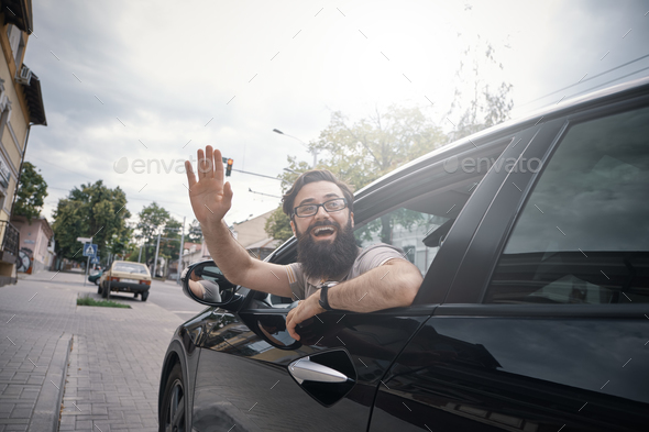 Cheerful man waving while driving a car Stock Photo by arthurhidden