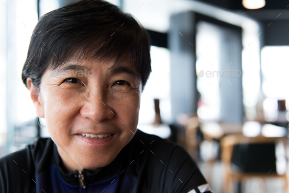 Senior Asian woman with coffee in cycling jersey