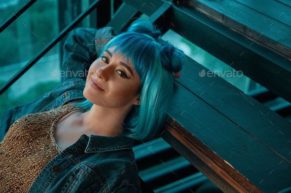Stylish woman wearing a blue wig laying on stairs looking to c Stock Photo by arthurhidden