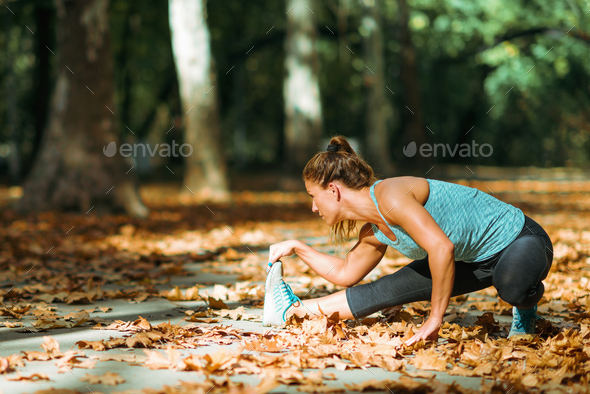 Woman stretching in the park, in the fall. Stock Photo by microgen