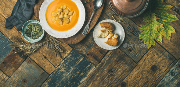 Fall pumpkin cream soup with croutons and seeds, wide composition - Stock Photo - Images