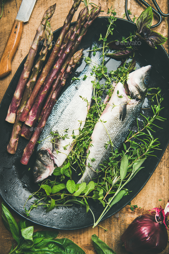 Raw uncooked sea bass fish with herbs and vegetables Stock Photo by sonyakamoz