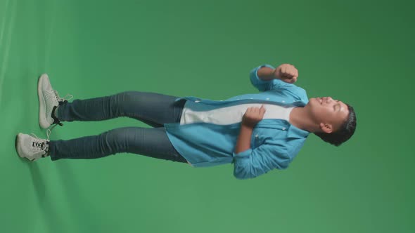 Side View Of Young Asian Man Dancing In A Green Screen Studio, Full Body alt