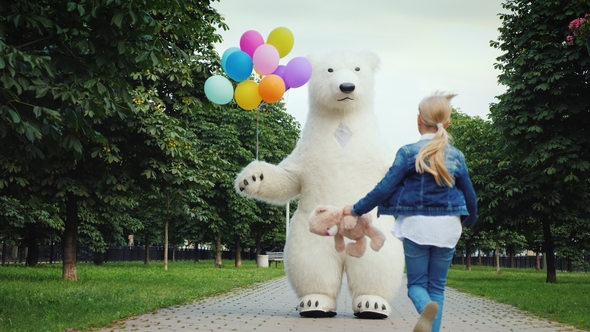 Happy Childhood. A Little Girl with Fair Hair Runs To Meet a Big White Bear, She Has a Teddy Bear in alt