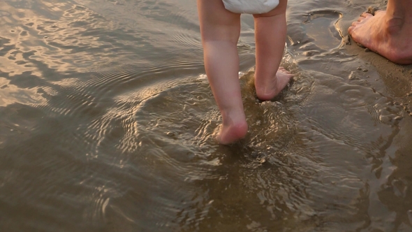 Child Walks on Water on Beach with Her Mother Splashing Water Around alt