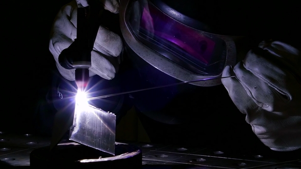 A Professional Worker Holds a Welding Machine in His Hands To Form a Welded Seam alt