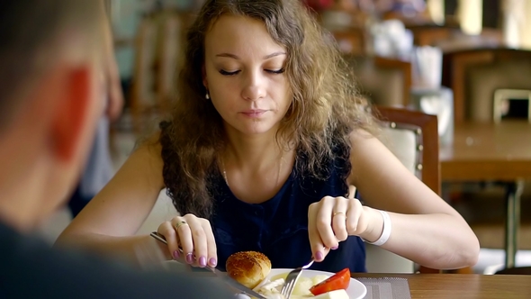 a Young Woman Eats at a Restaurant with Her Friend, a Lady Trying Food From Her Husband's Plate alt