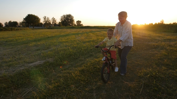 Grandmother Teaching Grandson To Ride a Bike