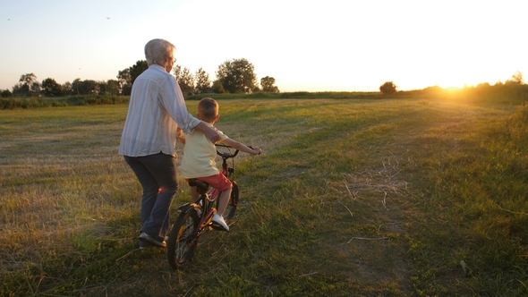 Back View of Boy Learning To Ride Bike with Granny alt