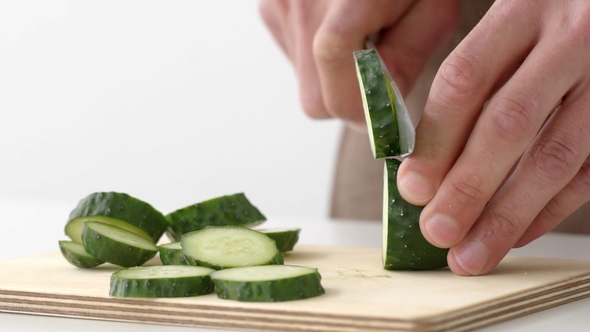 Cook's Hands Cut a Fresh Cucumber on a Board in alt