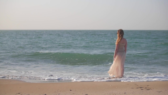 Young Woman Is Standing Alone on a Beach in Summer Day Looking on Sea and Holding Skirt