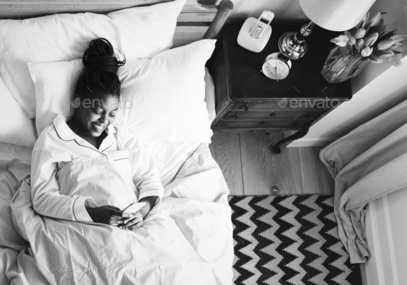 Smiling African American woman on bed using a cellphone Stock Photo by Rawpixel