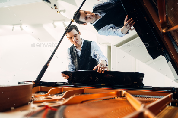 Pianist sets the grand piano before performance Stock Photo by NomadSoul1