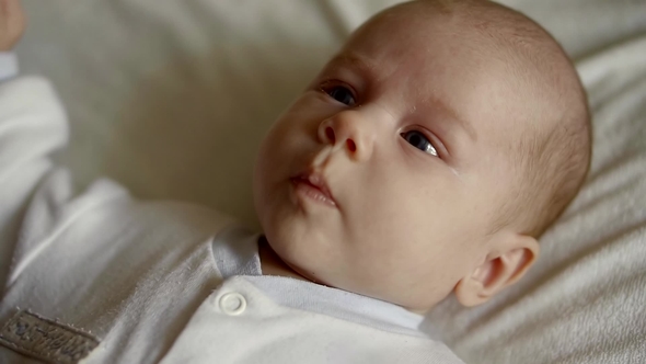 A Cute Little Child Looks at the Camera and Enjoys the White Bed alt