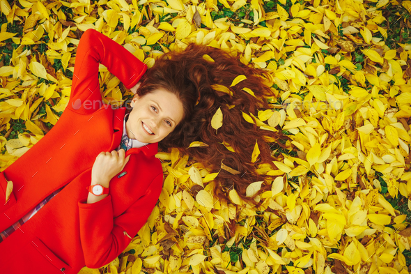 Young beautiful lady surrounded autumn leaves
