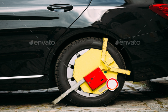 Wheel Of Car Was Locked With Yellow Clamped Wheel Lock By Traffi Stock Photo by Grigory_bruev