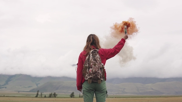 Female Traveler with Smoke Sticks Gives a Sign and Attracts Attention with Colored Smoke. Tourist