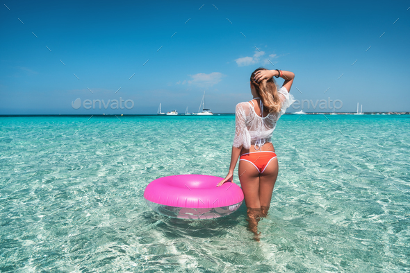 Young woman in white lace dress with swim ring in the sea - Stock Photo - Images